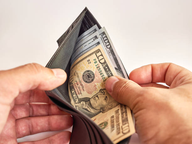 istock A man looks into a wallet full of dollars on a white background. 1615772639