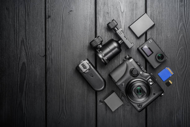 istock Digital compact and action cameras and equipment on black wooden plank table. top view. 1615775302