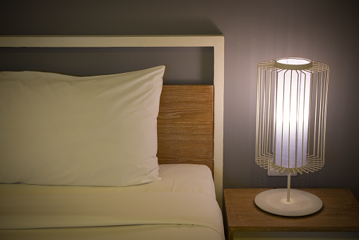 Bedroom with lamp lighting bedside table at night. Home interior design, lifestyle concept.