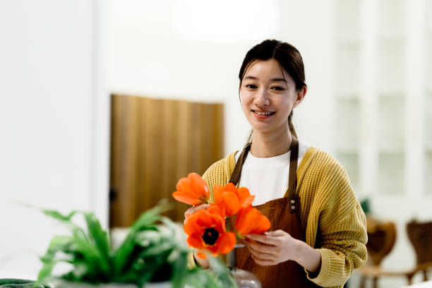 azjatycka młoda kobieta układająca bukiet kwiatów w szklanym wazonie w domu. - scented asia asian culture bunch zdjęcia i obrazy z banku zdjęć