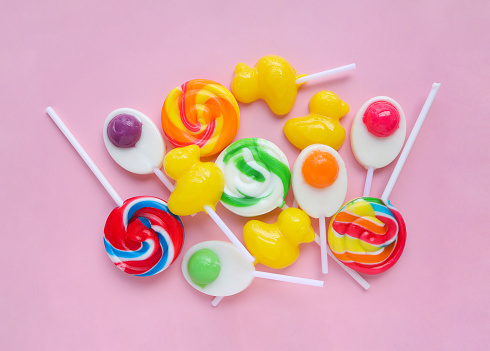 Colorful lollipops and different colored round candy. mixed collection of colorful candy on pink background. flat lay, Top view