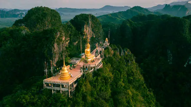 Photo of Beautiful aerial drone view of buddha statue on top of the mountain at sunrise, Wat Tham Sua (Seua) or (Tiger Cave Temple), Krabi, Thailand.