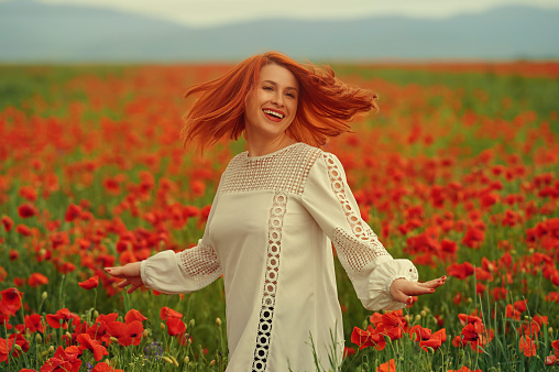 Beautiful woman in nature, feeling happy in the poppy field