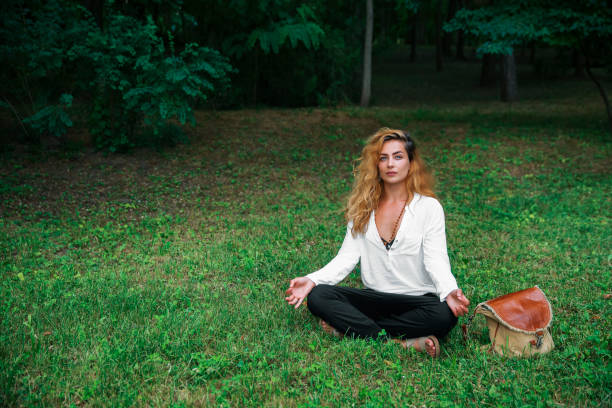 istock Woman meditating on green grass in the forest 1615888995