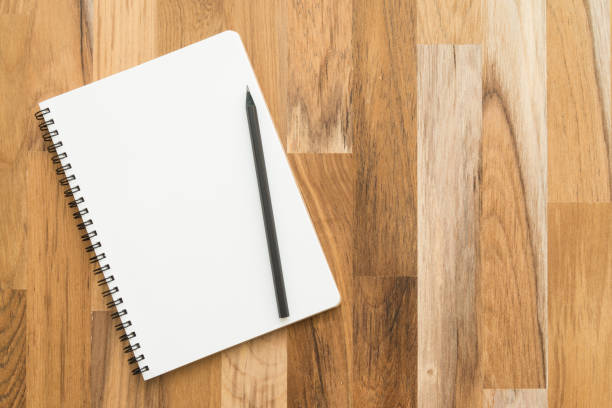 istock Flat lay of open blank spiral notepad or notebook and pencil on wooden table background. 1615899390