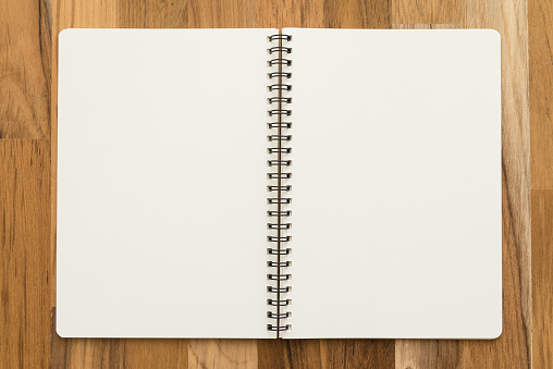 Flat lay of open blank spiral notepad or notebook on wooden table background. Office supply stationary, diary, organizer, business, education concept.