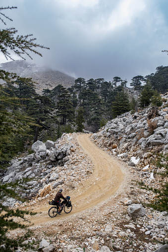 Overcast, there is some fog. Mountainous area. Steep area. Bkepacking cyclist driving on dirt road