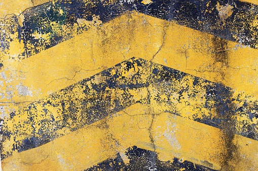 Worn weathered surface with diagonal yellow and black stripes