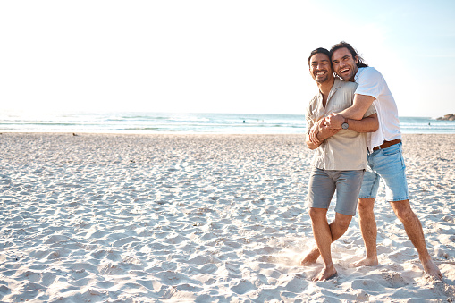 Love, hug and gay men on beach, mockup and laugh on summer vacation together in Thailand. Sunshine, ocean and romance, happy lgbt couple embrace in nature for fun holiday with pride, sea and sand.