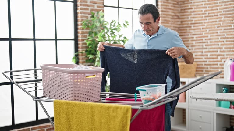 Middle age man hanging clothes on clothesline at laundry room