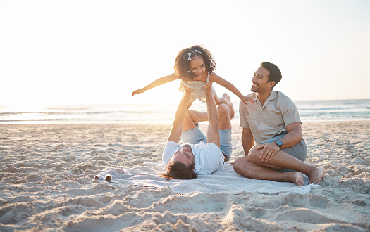 Lgbt family on beach, men with child and flying game on blanket for island holiday together in Hawaii. Love, play and sun, happy gay couple on tropical ocean vacation and parents with girl on sand.