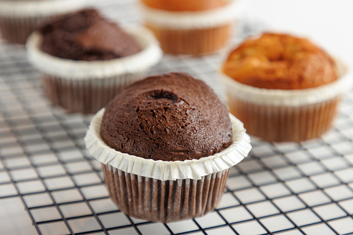 Close-up on baked chocolate muffin in wax paper cup, served on grid