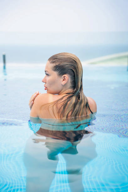 портрет красивой женщины в купальнике, отдыхающей в бассейне на курорте - swimming pool sensuality women sex symbol стоковые фото и изображения