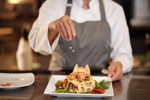 istock Cook Garnishing Pasta with Crushed Peanuts 1616038340