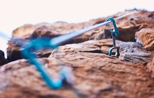 Rock climbing, mountain and closeup of rope and hook for adventure, freedom and extreme sports in nature. Fitness, hiking and carabiner, equipment or gear in stone for training, activity or challenge