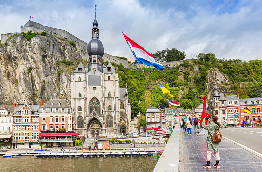 Tourists at the bridge with national flags in Dinant, Belgium