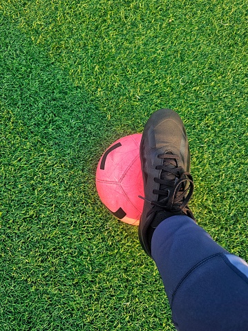 A Closeup portrait shot of soccer cleats on a ball in a green field with natural light