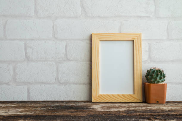 istock Photo frame on old wooden table with cactus pot over white brick wallpaper background. 1616071461