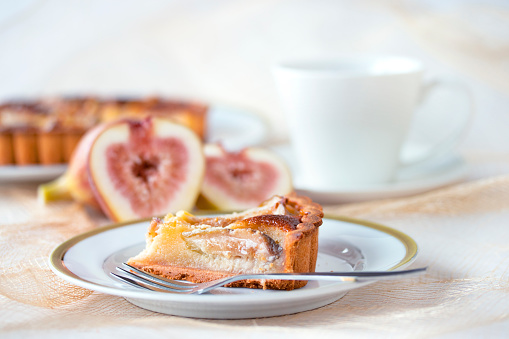 Homemade fig tart and coffee with fresh figs on white plate,