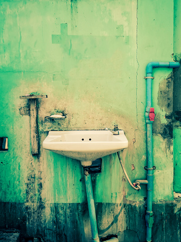 Old sink on a green delapidated wall