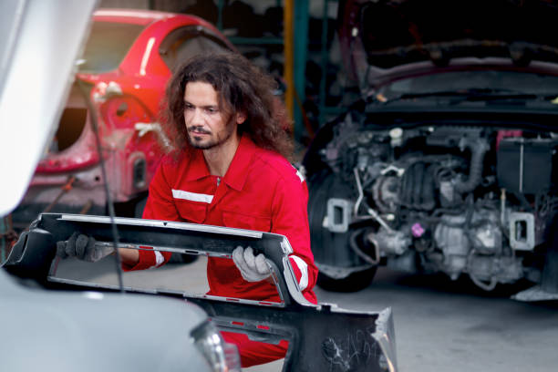 istock Long hair handsome mechanic man in red uniform works with engine vehicle, auto mechanic technician inspecting maintenance engine system of customer car automobile at garage car repair service shop. 1616123781