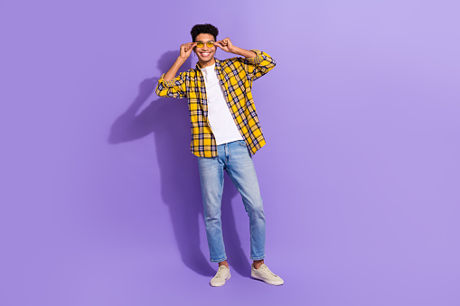 Full body photo of satisfied glad young person have good mood hands touch sunglass isolated on violet color background.