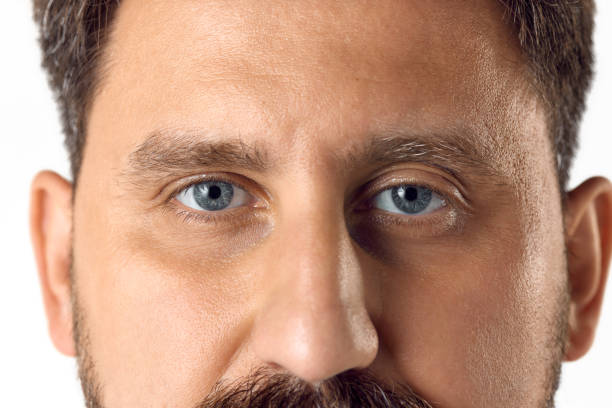 istock Cropped image of male face with blue eyes looking at camera against white studio background. Vision 1616148806