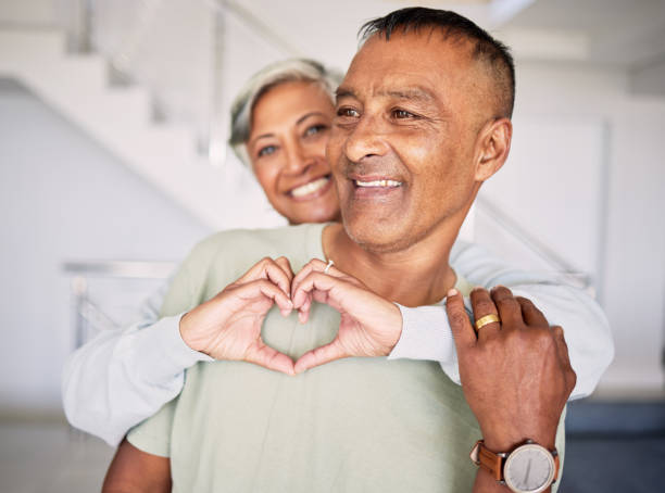 istock Heart, hands and couple in home for love, kindness and commitment to life partner, relationship or emoji sign. Mature, man, happy woman and hug with finger shape of care, support or trust in marriage 1616163494