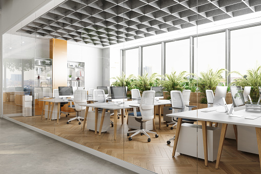 Outside View Of Eco-Friendly Open Plan Modern Office With Tables, Office Chairs And Plants
