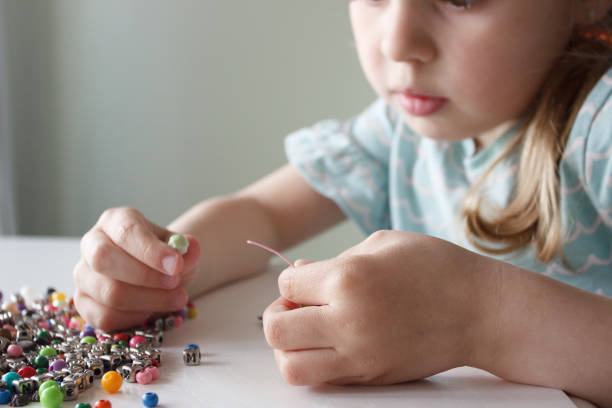 istock Process of making a bracelet from a thread and colored beads, concept of hobby 1616180241