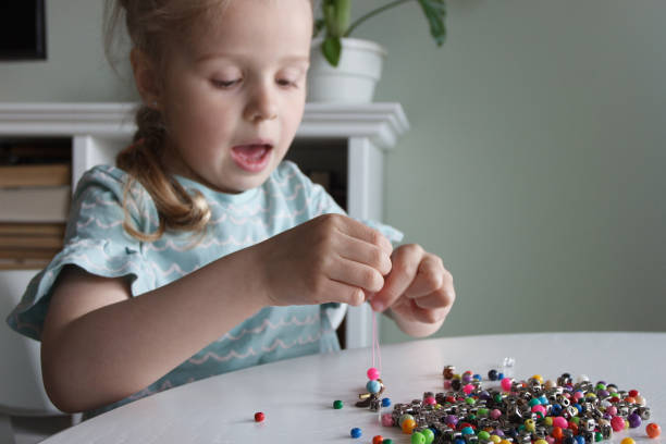 istock Process of making a bracelet from a thread and colored beads, concept of hobby 1616181332
