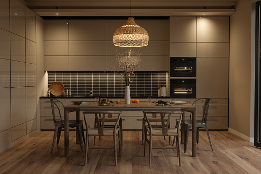 Modern Kitchen Interior With Beige Cabinets, Wood Dining Table And Chairs At Night