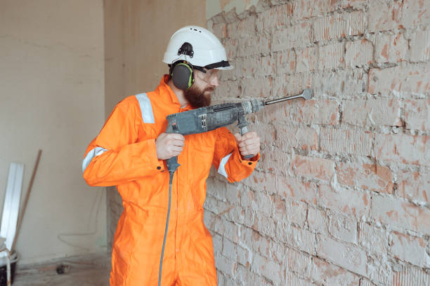 istock Worker removing old plaster from red brick wall by hammer drill. 1616201102