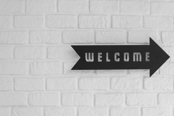 Welcome with right direction arrow  signboard on white brick wall.