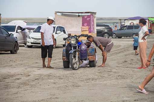 Lake Shalkar, Kazakhstan (Qazaqstan), 29.07.2023 - Men are examining a homemade tricycle on Lake Shalkar