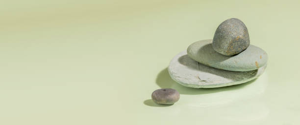 istock Several polished gray river stones, placed in a zen basin, on a plain green background, with copy space 1616214319