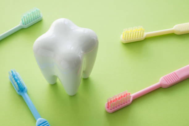 istock White tooth and colorful toothbrush on green background. 1616215012