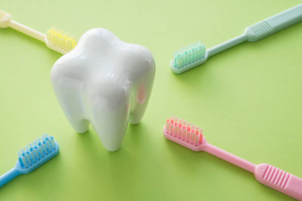 istock White tooth and colorful toothbrush on green background. 1616215397