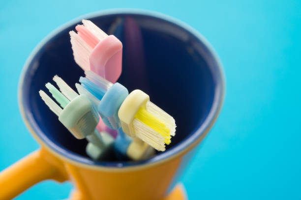 istock Close up colorful toothbrush in yellow ceramic cup with blue background. 1616215423