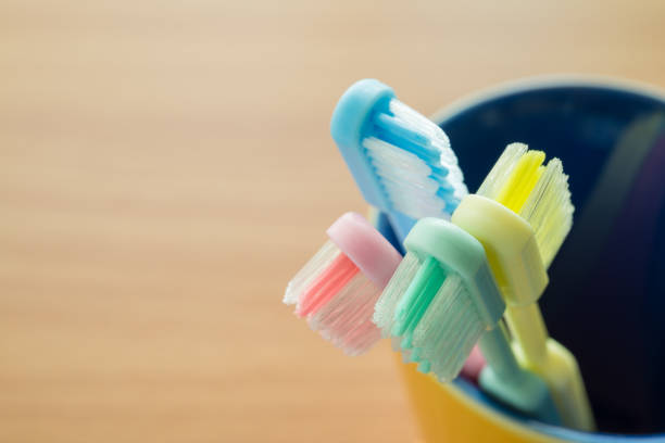 istock Close up colorful toothbrush in yellow ceramic cup with wooden table background. 1616215564