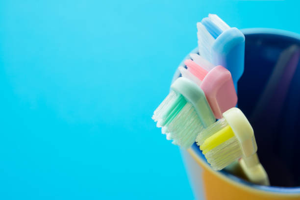 istock Close up colorful toothbrush in yellow ceramic cup with blue background. 1616215953