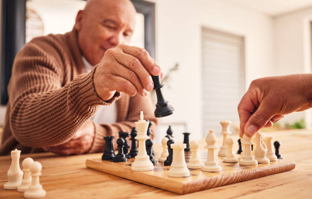 istock Senior man, home and chess for games, competition and focus with friends, strategy and problem solving. Elderly person, hands and board for contest with mindset, excited smile and moving at table 1616219339