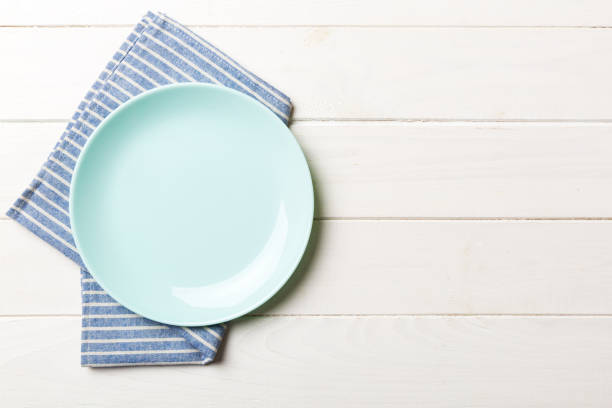 istock Top view on colored background empty round blue plate on tablecloth for food. Empty dish on napkin with space for your design 1616232054