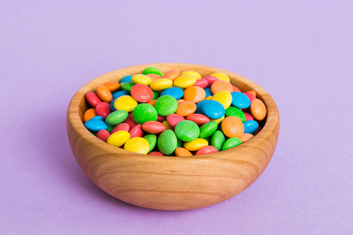 Multicolored candies in a bowl on a colored background. birthday and holiday concept. Top view with copy space.