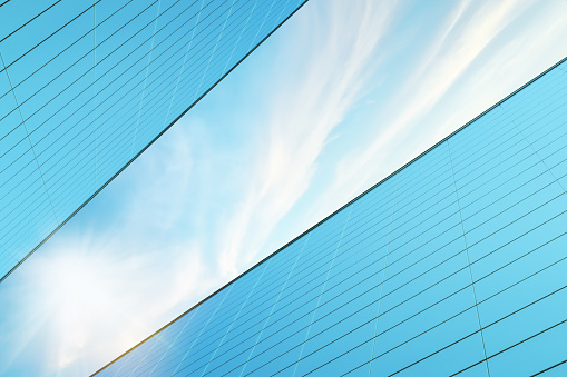 Modern Architecture building with aluminum facade. Blue sky, clouds and sunshine. Upward view from the ground.