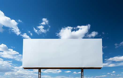 View of a white billboard sign with blue sky and clouds background
