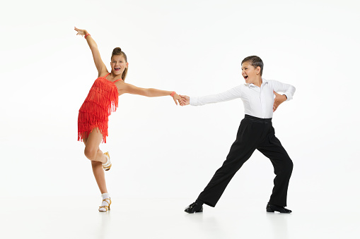 Boy and girl, children, friends making beautiful performance, dancing retro dance styles against white studio background. Concept of childhood, hobby, active lifestyle, performance, art, fashion