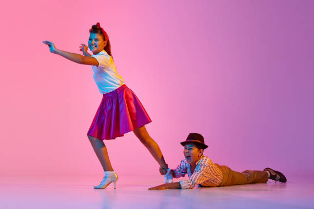 Friendship. Children making creative dance performance against pink studio background in neon light Friendship. Children making creative dance performance against pink studio background in neon light. Concept of childhood, hobby, active lifestyle, performance, art, fashion rockabilly boys stock pictures, royalty-free photos & images