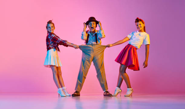Children in stylish retro clothes making performance, dancing against pink studio background in neon light Children in stylish retro clothes making performance, dancing against pink studio background in neon light. Concept of childhood, hobby, active lifestyle, performance, art, fashion rockabilly boys stock pictures, royalty-free photos & images
