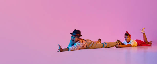 Emotional dance. Children, boy and girl in retro clothes performing against pink studio background in neon light Emotional dance. Children, boy and girl in retro clothes performing against pink studio background in neon light. Concept of childhood, hobby, active lifestyle, performance, art, fashion. Banner rockabilly boys stock pictures, royalty-free photos & images